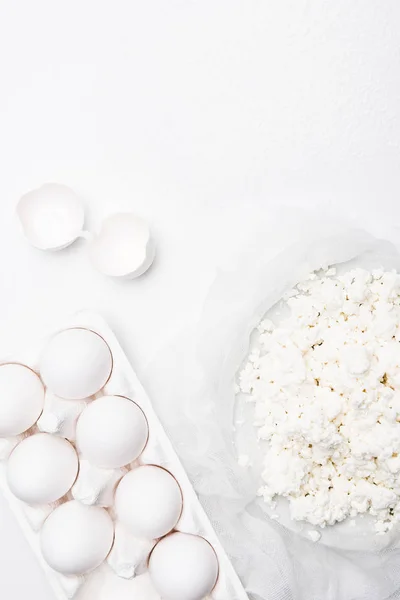 Top view of homemade cottage cheese and eggs on white surface — Stock Photo