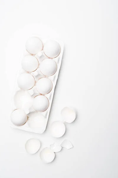 Top view of chicken eggs in carton on white surface — Stock Photo