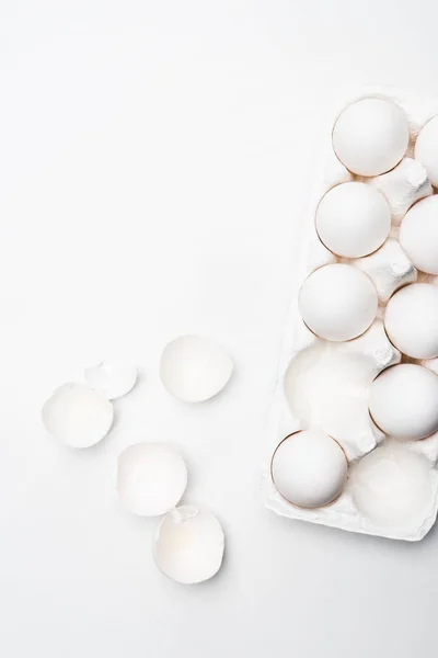 Vue du dessus des œufs de poulet crus en carton sur la surface blanche — Photo de stock