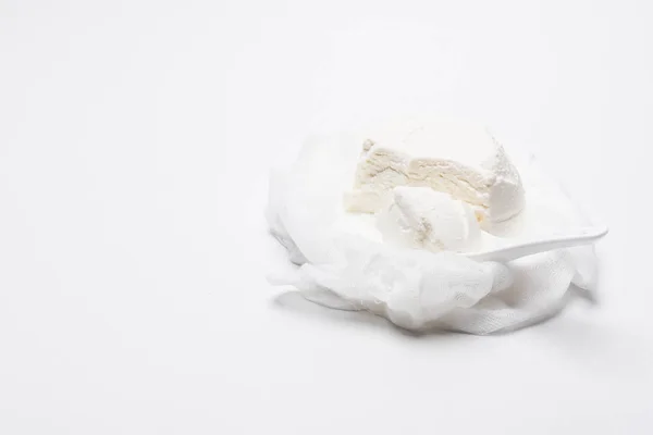 Homemade cottage cheese on cheesecloth with spoon on white surface — Stock Photo