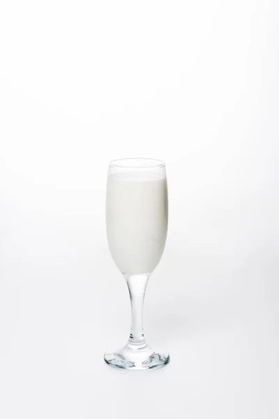 Close-up shot of fresh milk in wineglass on white surface — Stock Photo