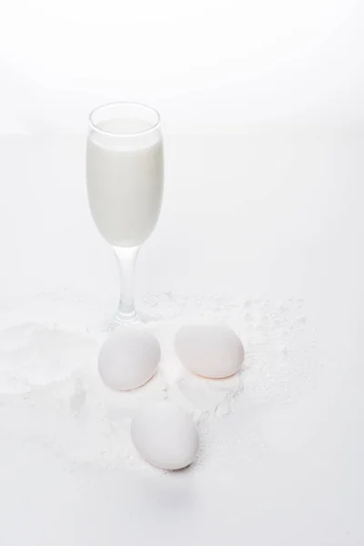Huevos de pollo con harina y leche en la superficie blanca - foto de stock
