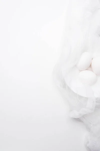 Top view of chicken eggs in cheesecloth on white surface — Stock Photo