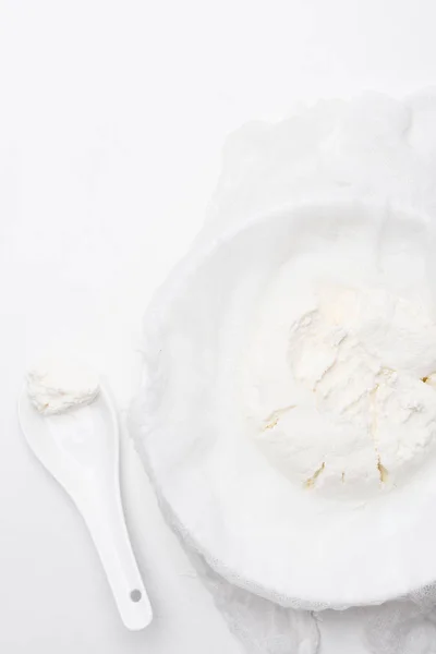 Top view of cottage cheese on cheesecloth with spoon on white surface — Stock Photo