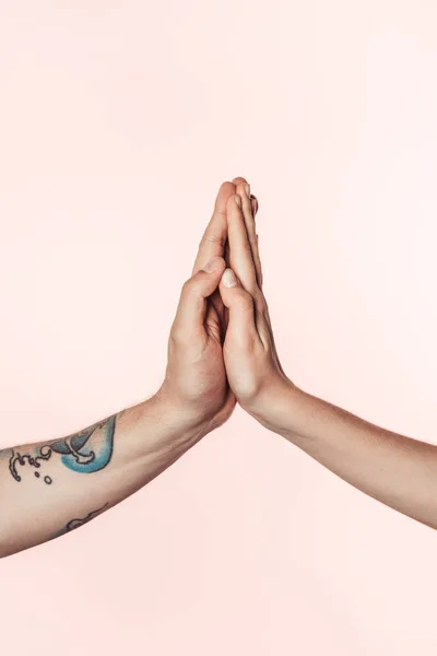 Cropped shot of tattooed man and woman holding palms together isolated on pink background — Stock Photo