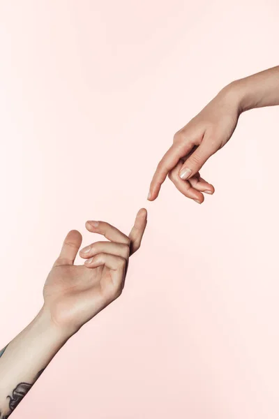 Abgeschnittene Aufnahme eines tätowierten Mannes und einer tätowierten Frau, die sich einander nähern, indem sie Finger isoliert auf rosa Hintergrund zeigen — Stockfoto