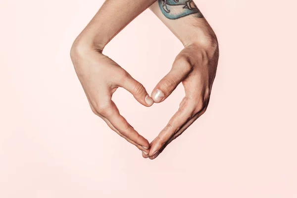 Cropped shot of woman and tattooed man doing heart symbol by hands isolated on pink background — Stock Photo