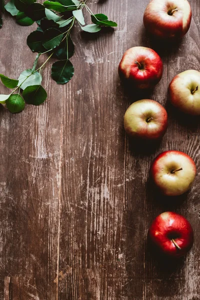 Flache Lage mit arrangierten reifen Äpfeln und grünen Blättern auf Holztischplatte — Stockfoto