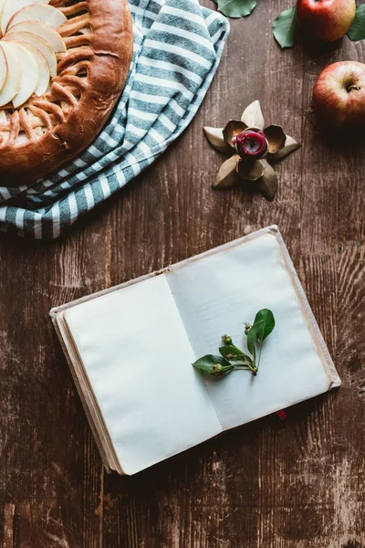 Vue du haut du carnet vide, tarte aux pommes maison et bougie sur la surface en bois — Photo de stock