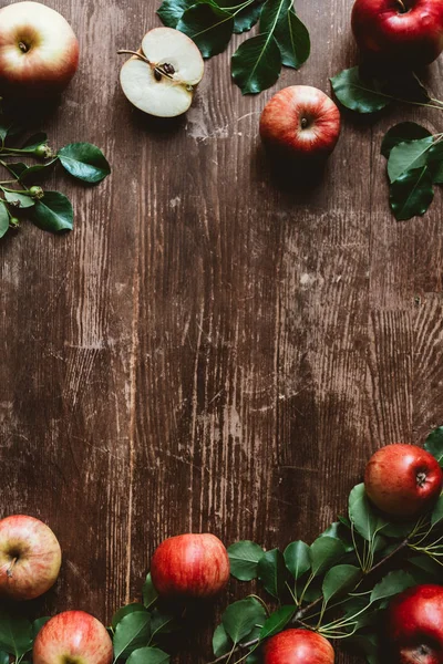 Flat lay with arranged ripe apples and green leaves on wooden tabletop — Stock Photo