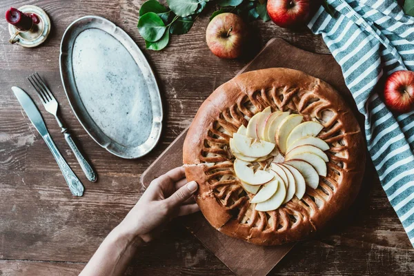 Частковий вид жінки, яка бере шматок домашнього яблучного пирога на дерев'яній обробній дошці — стокове фото