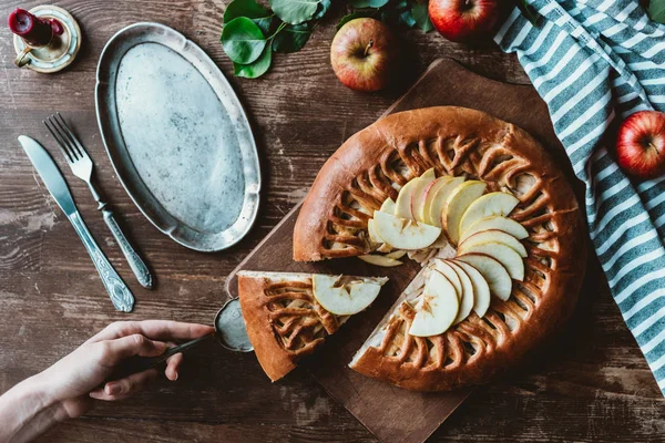 Частковий вид жінки з сервером торта, що бере шматок домашнього яблучного пирога на дерев'яній обробній дошці — стокове фото