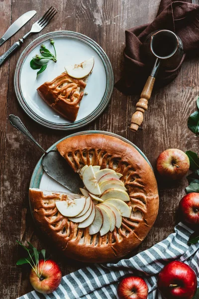 Flat lay com pedaço de torta de maçã caseira, talheres e cafeteira dispostos em superfície de madeira — Fotografia de Stock