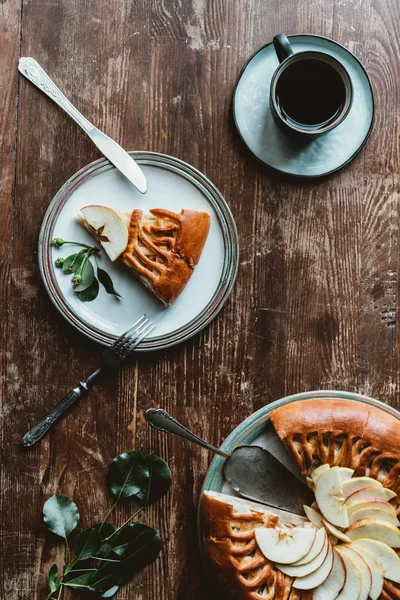 Acostado plano con trozo de tarta de manzana casera, taza de café y manzanas frescas en la superficie de madera - foto de stock