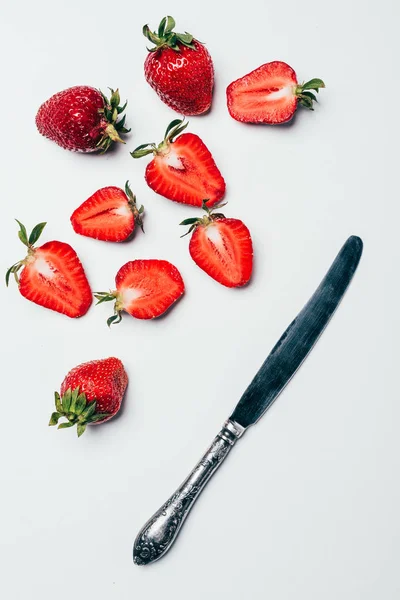 Vista superior de fresas frescas en rodajas maduras y cuchillo sobre blanco - foto de stock