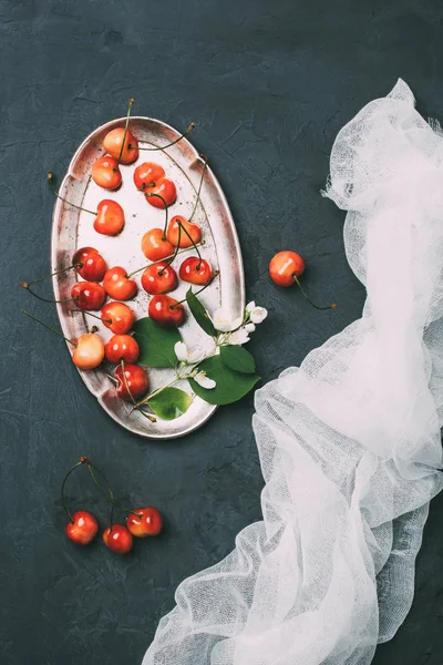 Vue de dessus des cerises douces fraîches et des fleurs de jasmin sur noir — Photo de stock