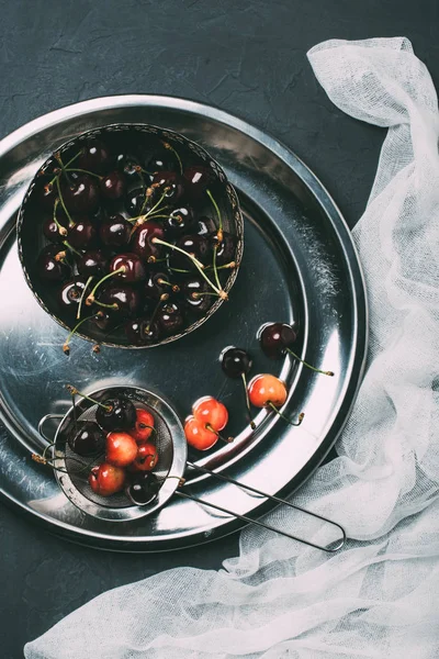 Top view of fresh sweet cherries in shiny metal plate on black — Stock Photo