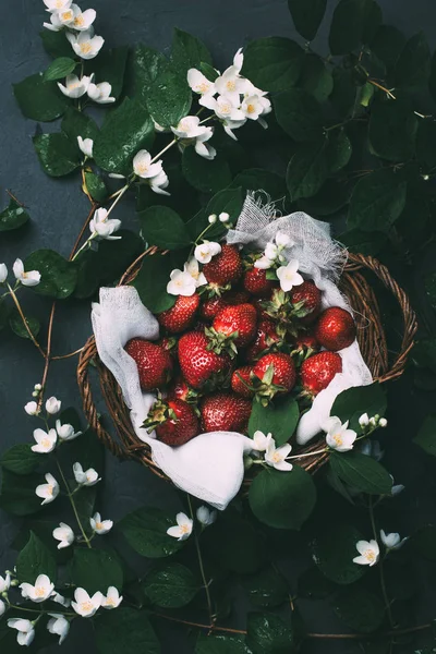 Vue de dessus de belles fleurs de jasmin et de fraises mûres sucrées dans le panier — Photo de stock