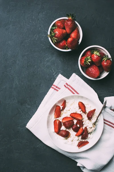 Blick von oben auf gesunden Quark und frische reife Erdbeeren in Schalen auf schwarz — Stockfoto