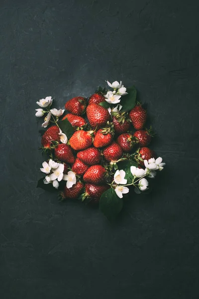Draufsicht auf frische reife Erdbeeren und Jasminblüten auf schwarz — Stockfoto