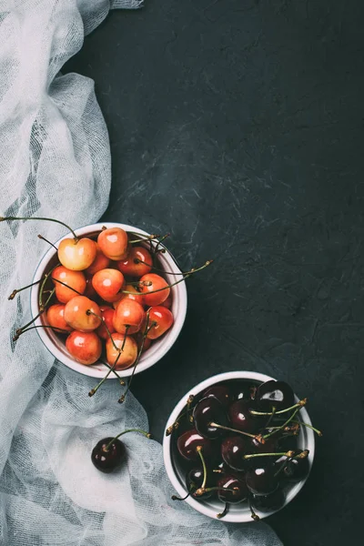 Top view of sweet cherries in bowls on black — Stock Photo