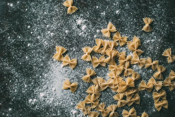 Elevated view of farfalle pasta on table covered by flour — Stock Photo