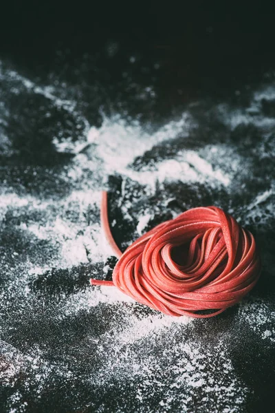 Close up view of red raw tagliatelle pasta on table covered by flour — Stock Photo