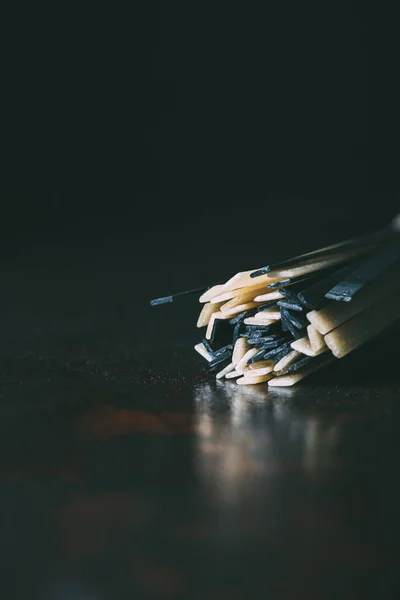 Nahaufnahme klassischer und schwarzer Linguine-Pasta auf schwarzem Hintergrund — Stockfoto