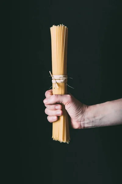 Cropped image of holding spaghetti wrapped by ribbon isolated on black background — Stock Photo