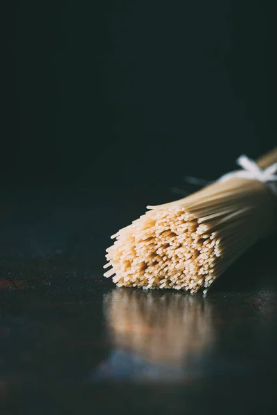 Closeup view of spaghetti wrapped by ribbon on black background — Stock Photo