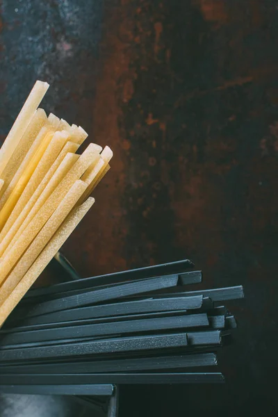 Top view of raw black and classical linguine pasta in pan on metal table — Stock Photo