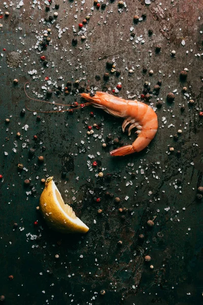 Top view of shrimp and lemon slice on surface with salt and black pepper — Stock Photo