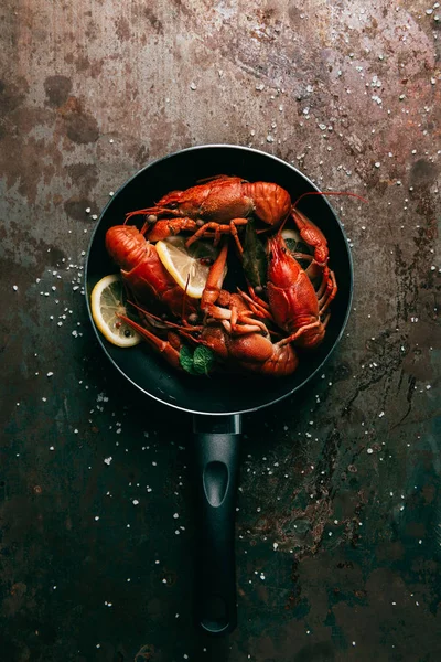 Top view of crayfishes with bay leaf, mint and lemon slices on frying pan — Stock Photo
