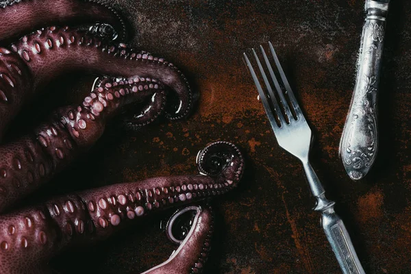 Top view of big octopus with fork and knife on rusty metal surface — Stock Photo