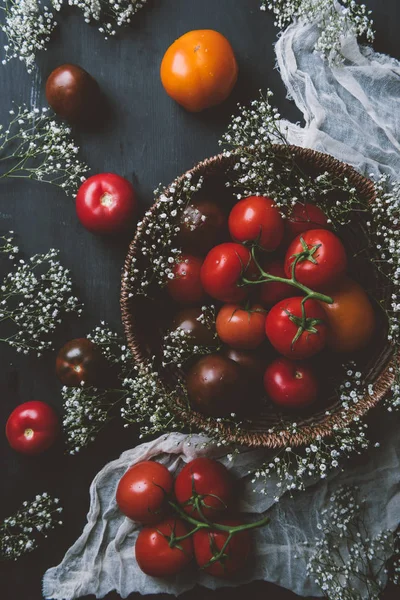 Top view of fresh red tomatoes in wicker bowl with white flowers — Stock Photo