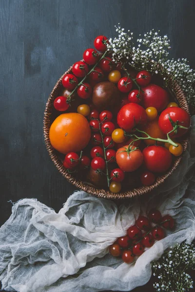 Вид помидоров в плетеной чаше с белыми цветами — стоковое фото