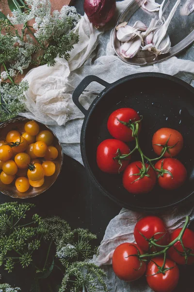 Vista superior de tomates cereja amarelos e tomates vermelhos na frigideira na gaze no fundo de madeira com flores de salsa — Fotografia de Stock