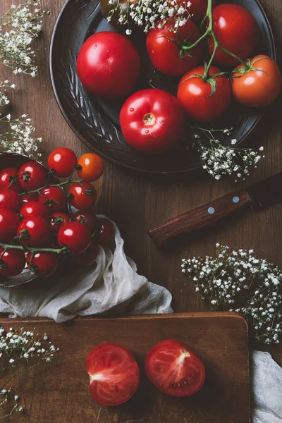 Vista superior de tomates frescos em placa de cerâmica e placa de corte com faca — Fotografia de Stock