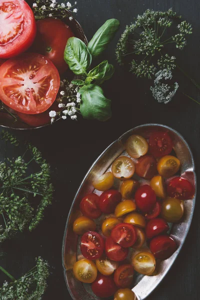 Vista superior de tomates cereja amarelos e vermelhos cortados em placa de metal com flores — Fotografia de Stock