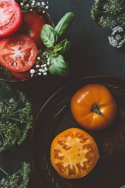 Draufsicht auf rote und gelbe Tomaten mit Blumen und Basilikum — Stockfoto