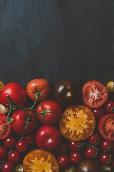 Vista superior de diferentes tomates rojos y amarillos sobre fondo de madera con espacio para copiar - foto de stock