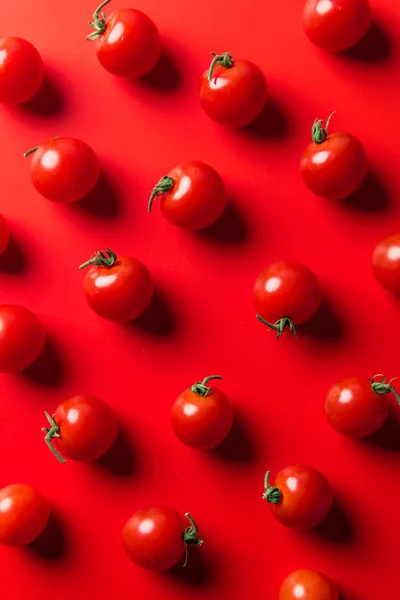 Vue du dessus du motif de tomates cerises sur la surface rouge — Photo de stock