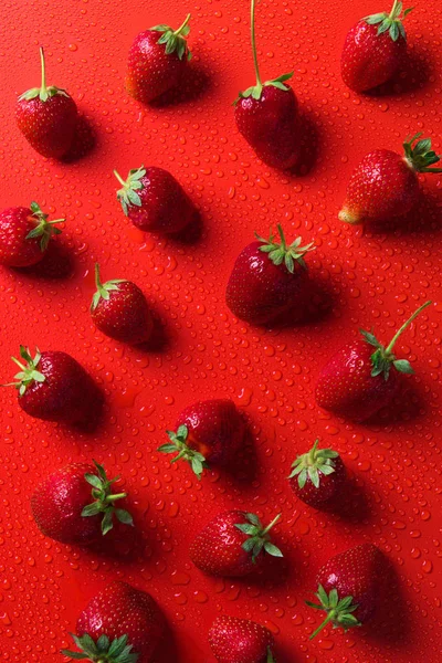 Vista superior de las fresas en la superficie roja con gotas de agua — Stock Photo