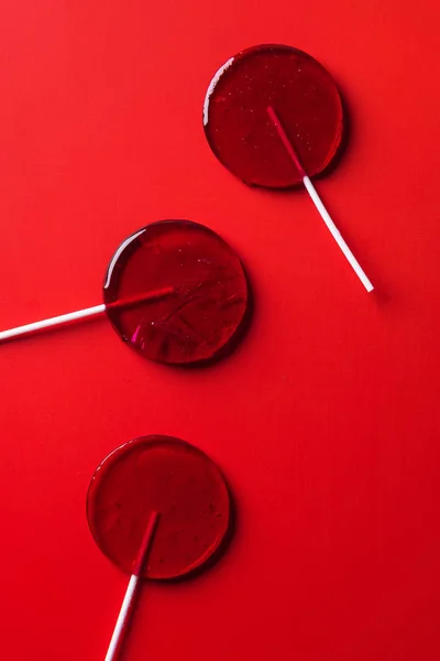 Top view of three lollipops on red surface — Stock Photo