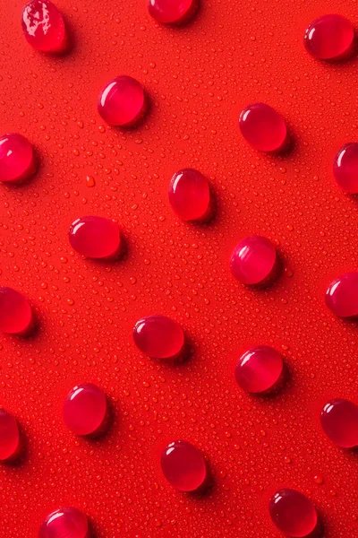 Top view of collection of candies on red surface with water drops — Stock Photo