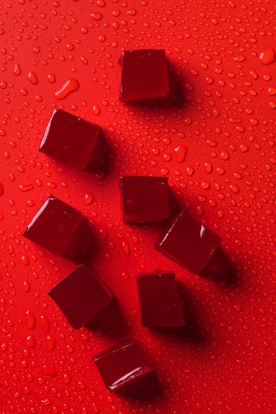 Vista superior de doces na superfície vermelha com gotas de água — Fotografia de Stock
