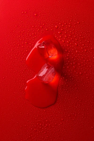 Top view of melting ice cubes on red surface with water drops — Stock Photo