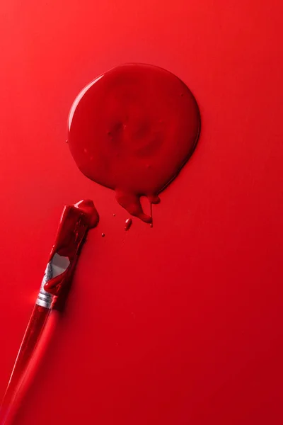 Vue de dessus du pinceau et de l'encre rouge sur la surface rouge — Photo de stock