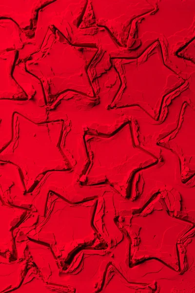 Top view of shapes of cookie cutters in shape of stars on red powder — Stock Photo