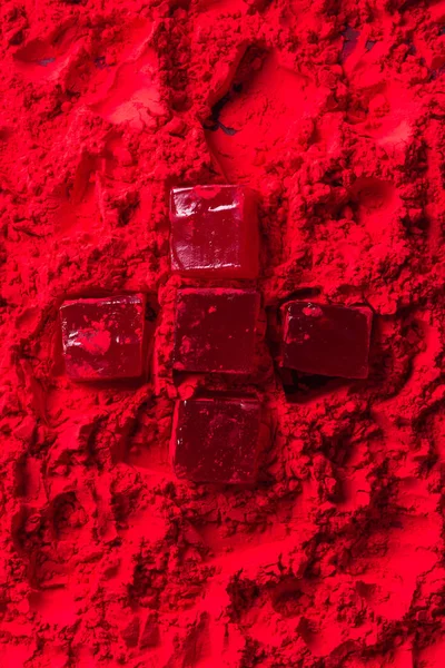 Top view of candies in shape of cross on red powder — Stock Photo
